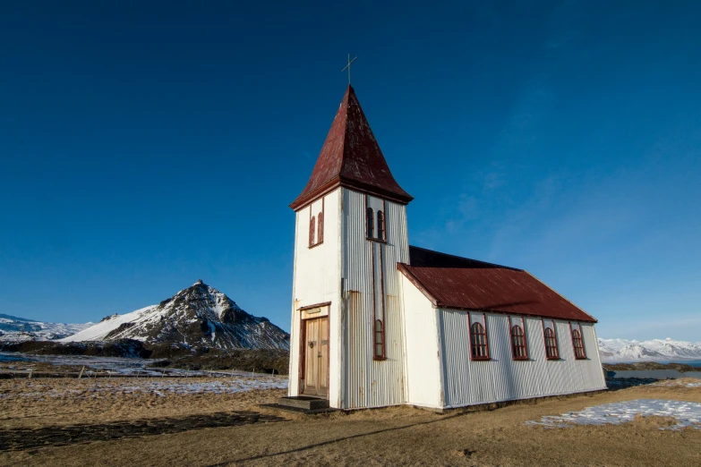 a church stands in an area with snowy mountains