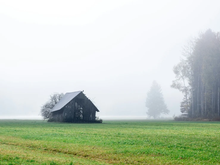 an old barn sitting in the middle of a field