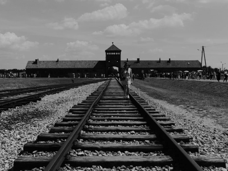 a group of people walking along railroad tracks near a building