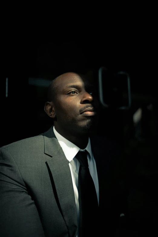 man in black suit and white shirt with a dark background