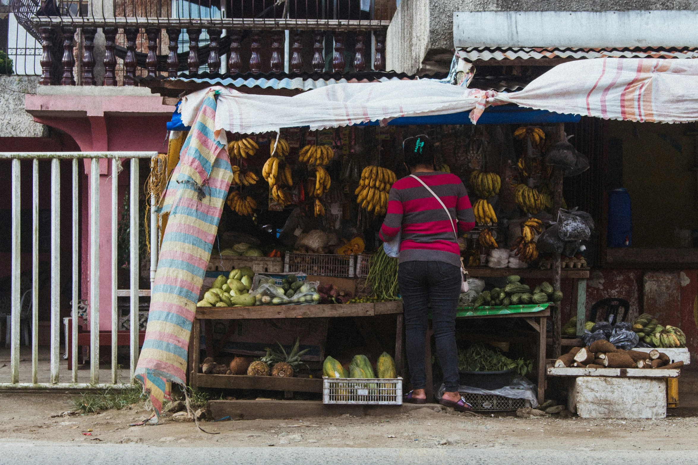 a woman standing in front of a fruit stand