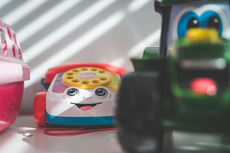 a little red toy car sitting next to a toy phone