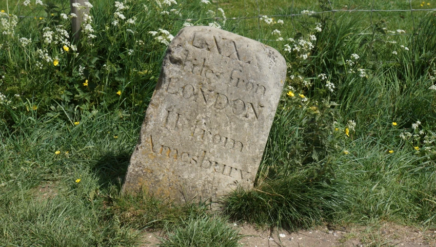 large old granite marker with writing in grassy area