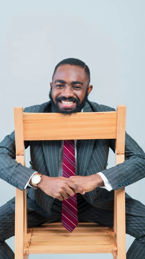 a bearded man is sitting on a wooden chair