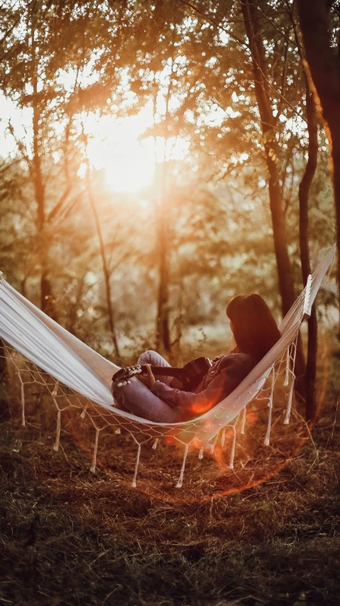 a woman sleeping in a hammock surrounded by trees