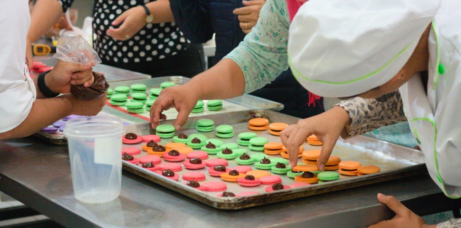 a number of people near one another with a tray of cakes on it