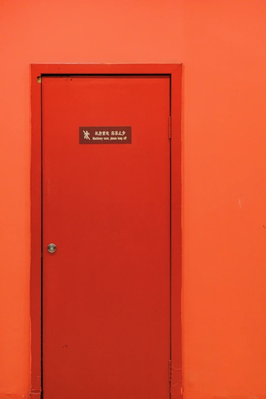 a red doorway sits in the corner of an orange wall