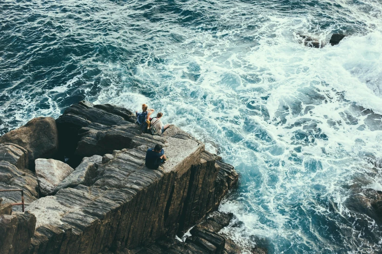 a couple of people standing on a cliff over some ocean