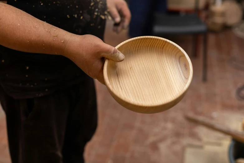 a wooden bowl held by a man, that is slightly open