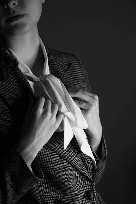 a woman in a suit is pulling on a white tie