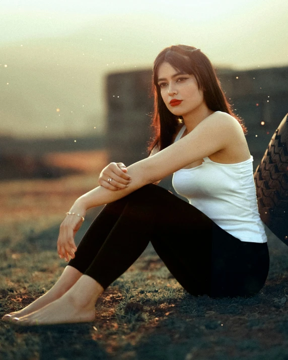 a girl sitting on the ground in front of a tire