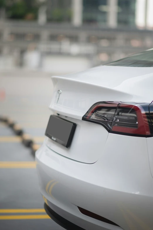 the back end of a white sports sedan parked on a parking lot