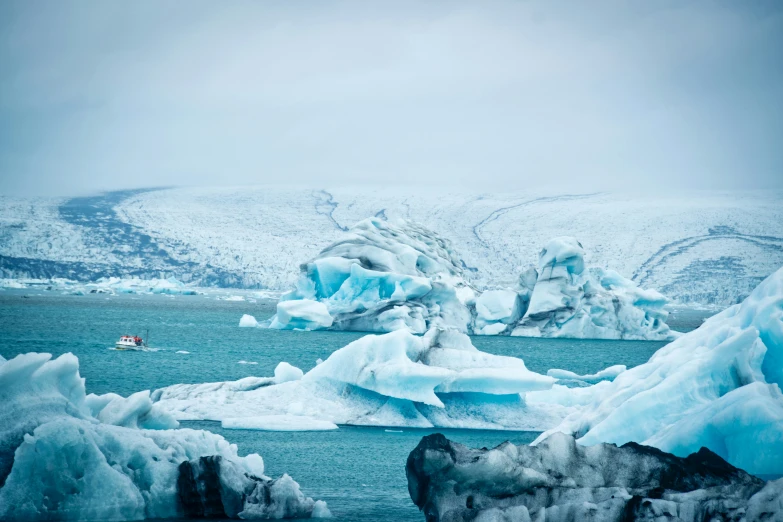 a boat traveling through the water near a huge iceberg