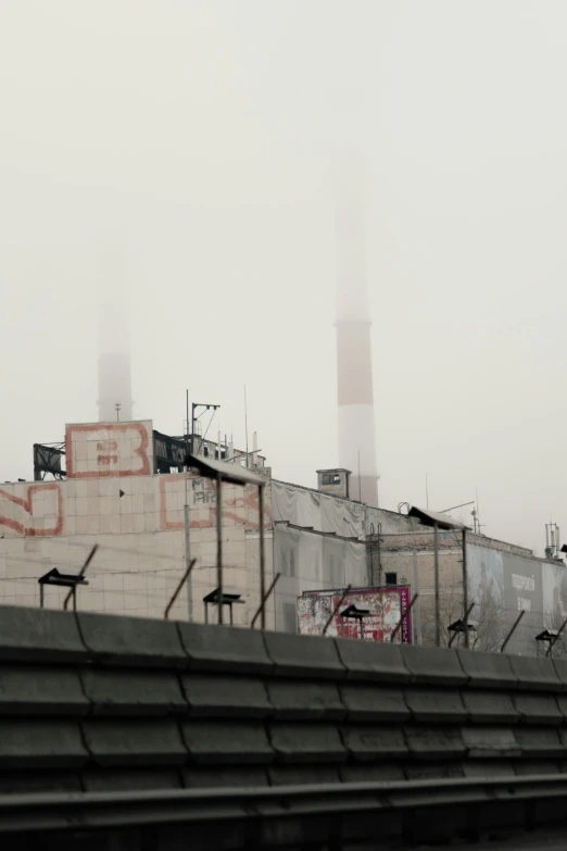 industrial buildings sit behind a fence with chairs and a clock