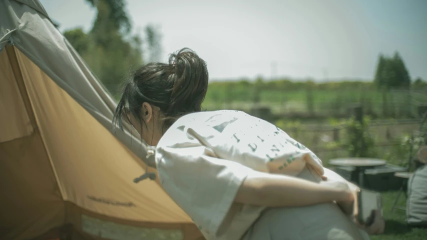 a woman sitting outside of her tent, hugging her back