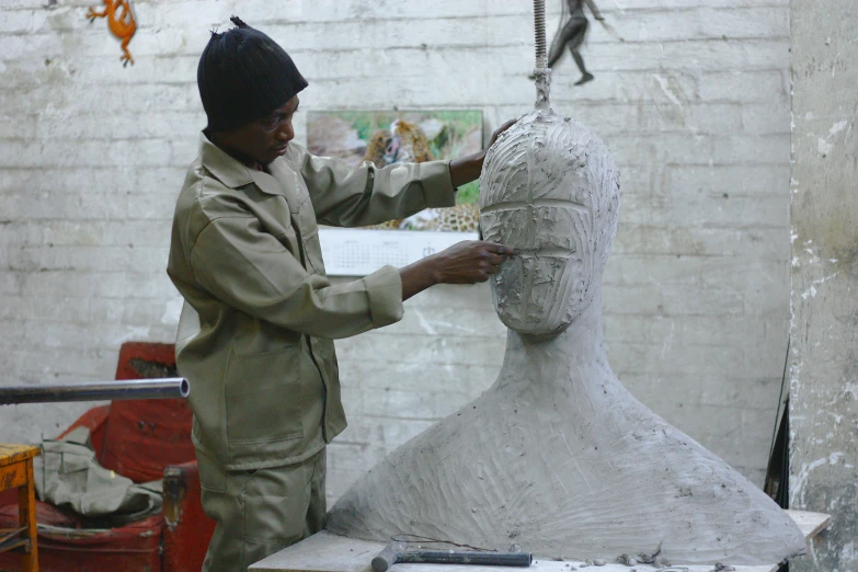 a man working on a clay statue in a warehouse