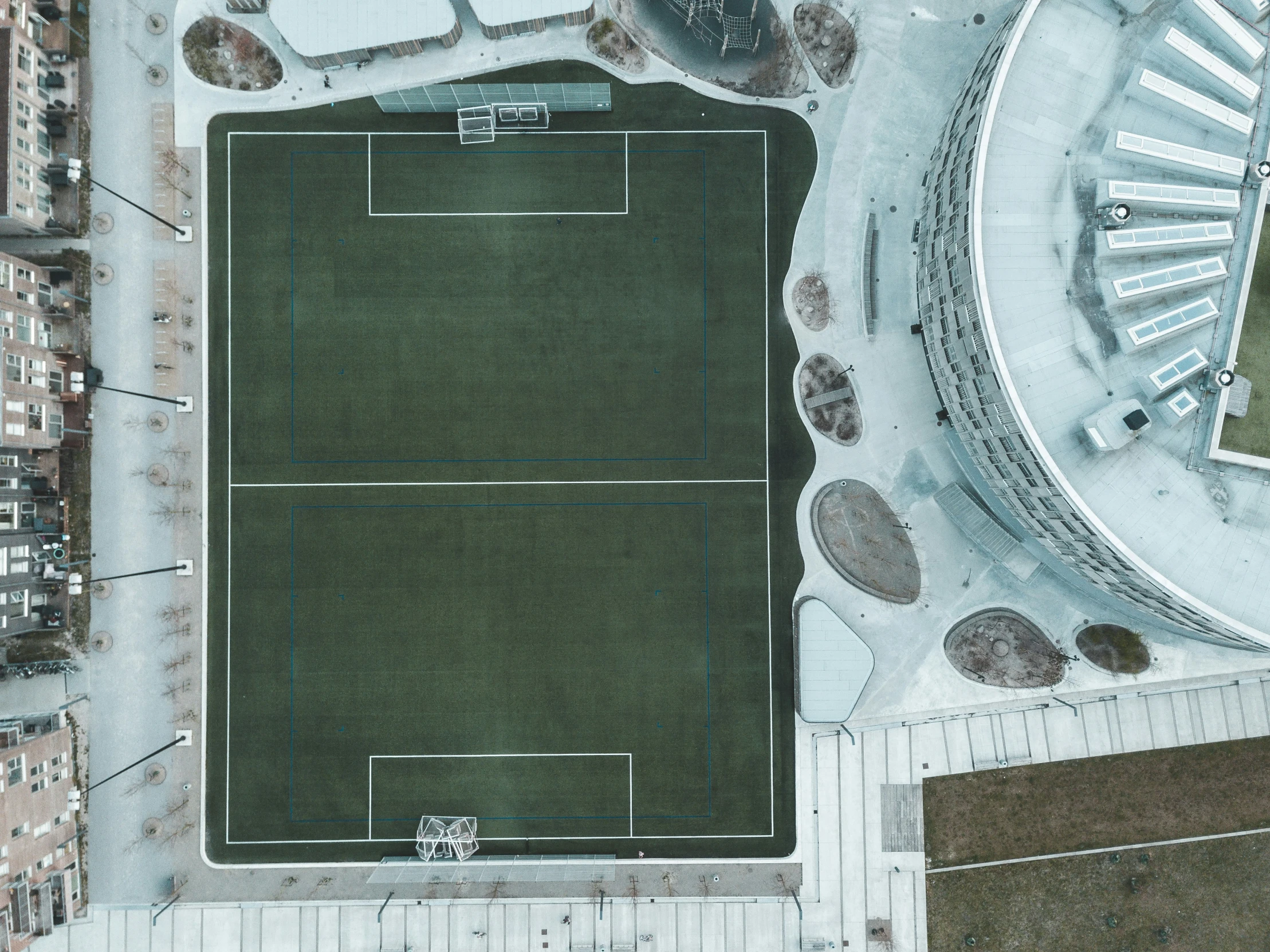 an aerial view of a tennis court, with snow covered ground and lots of trees