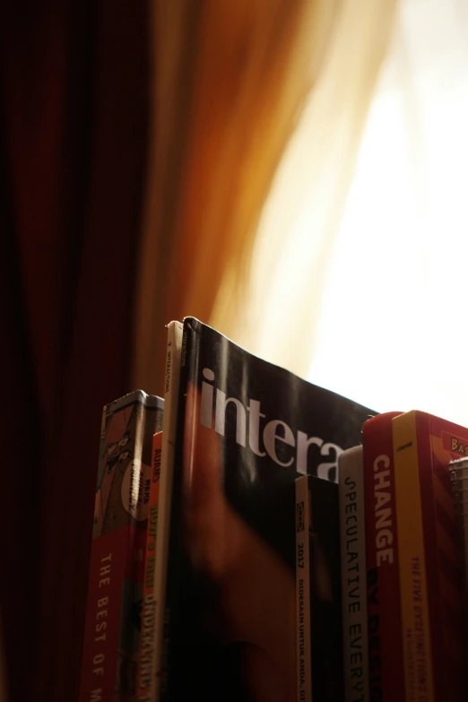 several books sit on the shelf and are placed against a curtain