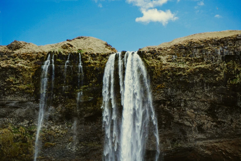 a waterfall and a blue sky with clouds