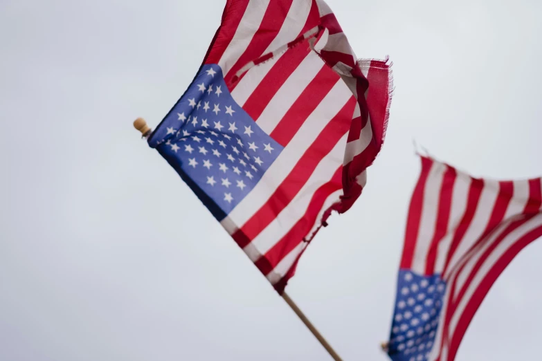 two american flags flying side by side on top of each other