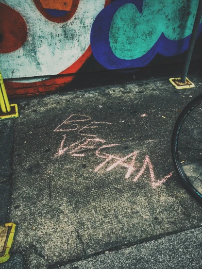 a graffiti written in chalk on the ground in front of a building