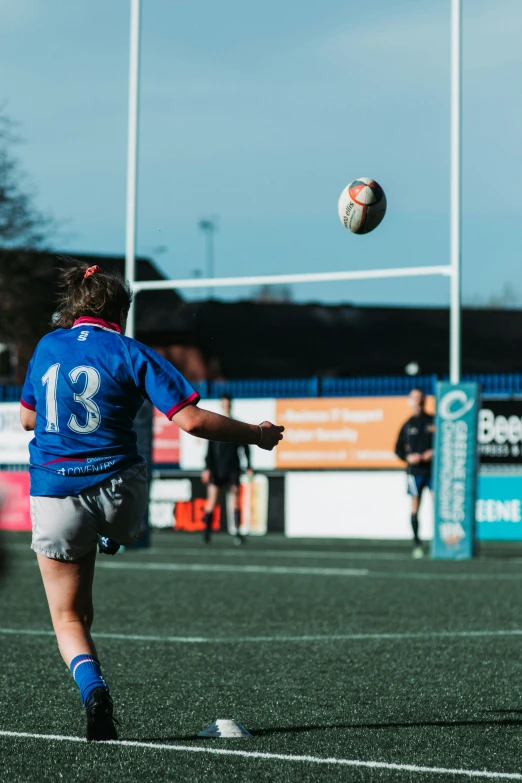 a girl in blue jersey kicking around a soccer ball