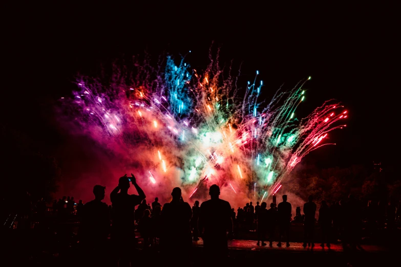 some people watching colorful fireworks and people taking pictures