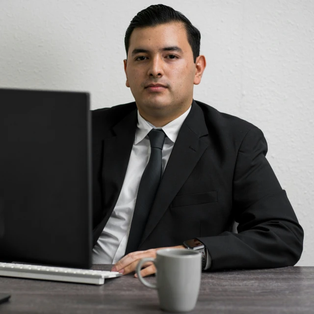 man in business suit sitting at desk looking into computer monitor
