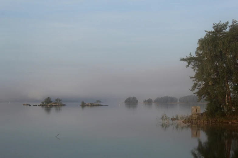 misty water, with a few islands and trees in the foreground