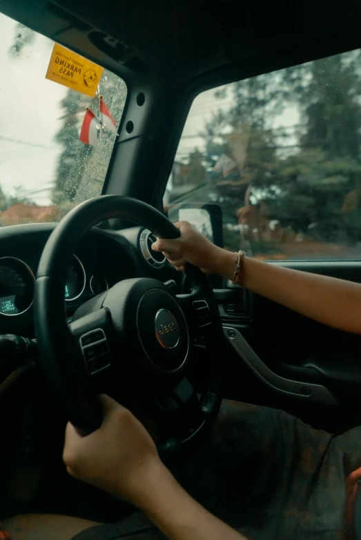 a person driving a car with a driver's arm on the steering wheel