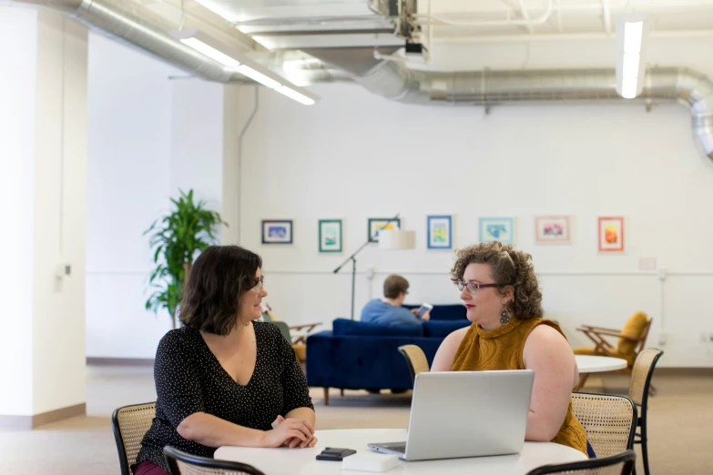 a woman and another person sitting at a table talking