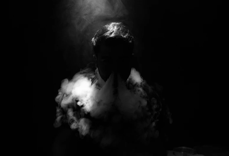 black and white po of a person sitting in the smoke