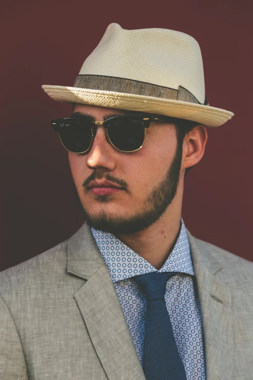 a man wearing a hat and glasses on a red background