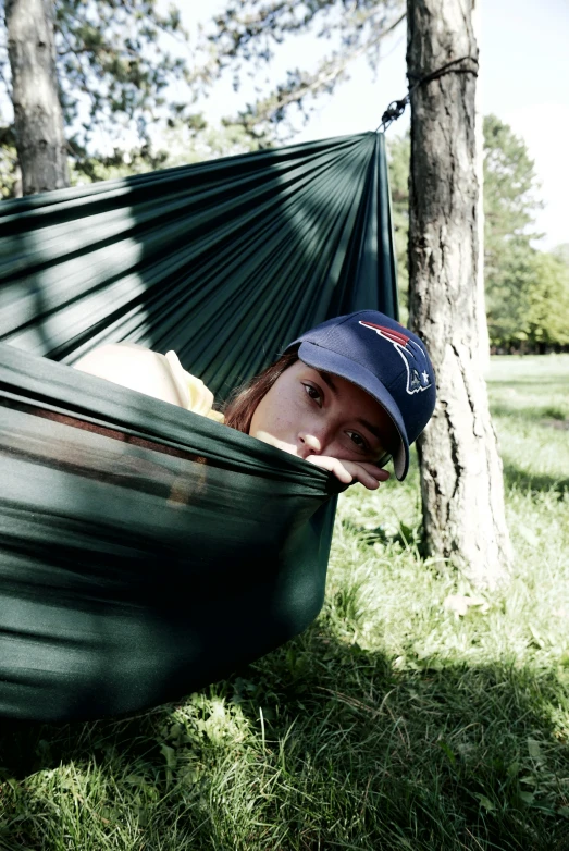 a guy relaxing in a green hammock while staring to his left