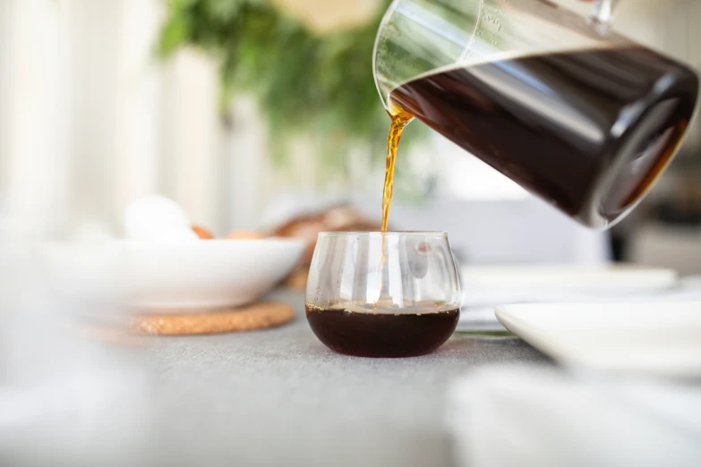 there is oil pouring into a glass cup