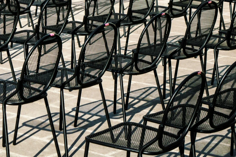 many chairs lined up in a row with the shadows off them