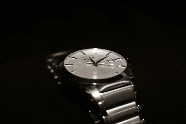 a silver watch on a black background with a small candle on the second one side