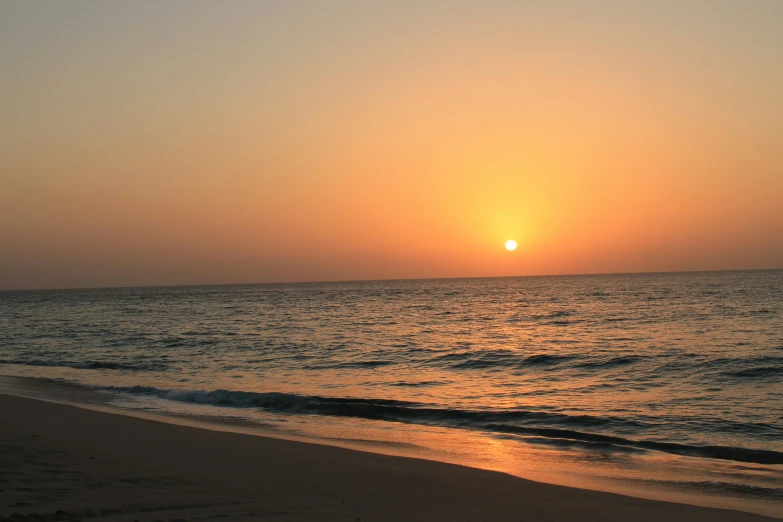 the sun is setting on a beach at dusk