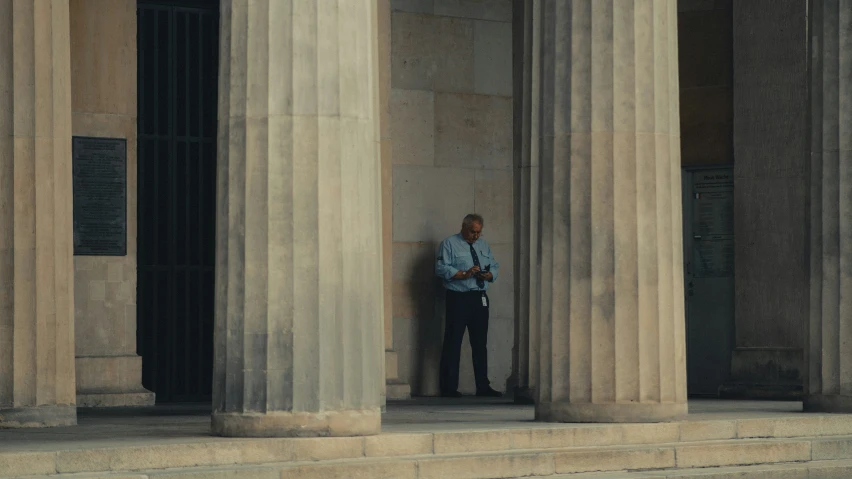 a man standing on the steps next to three tall pillars