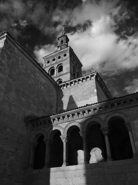 an old building with columns and arches in front of clouds