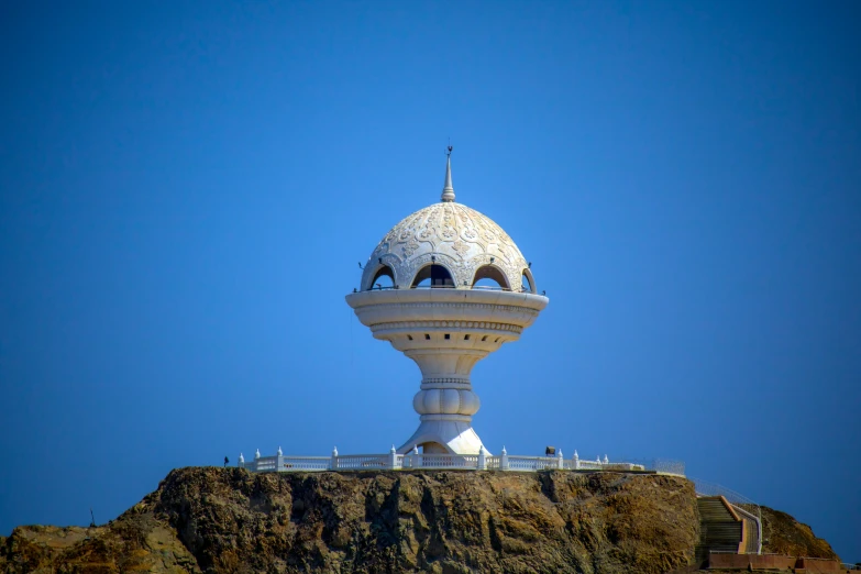 this unusual white tower sits atop a rocky hill