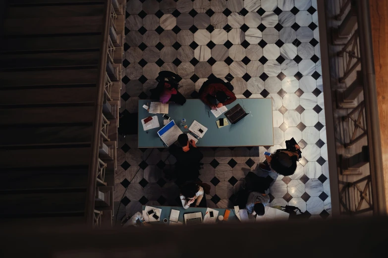 overhead view of four people sitting at a table with laptops