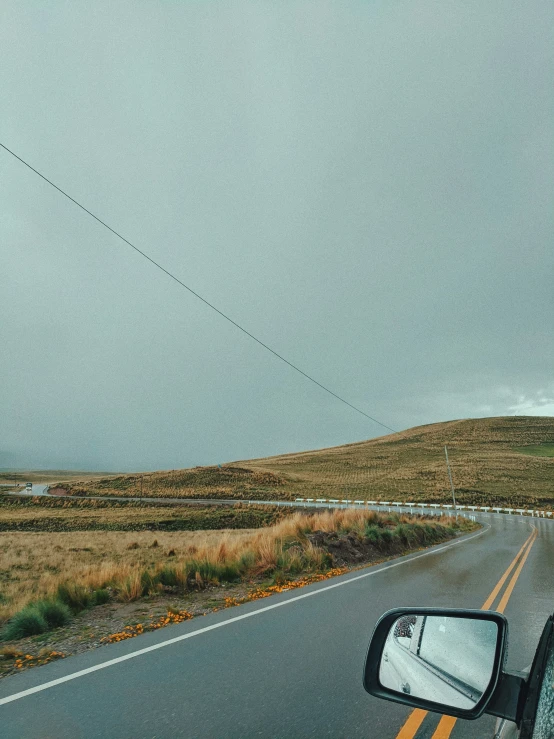 road going down mountains towards a field and power line