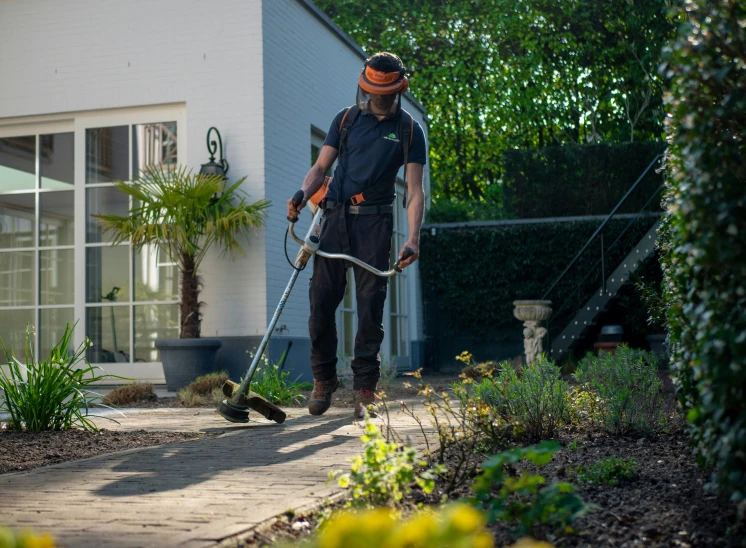 a man with an orange hat using a weeder