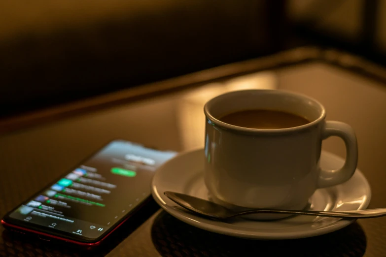 a coffee cup and a cell phone are setting on a table