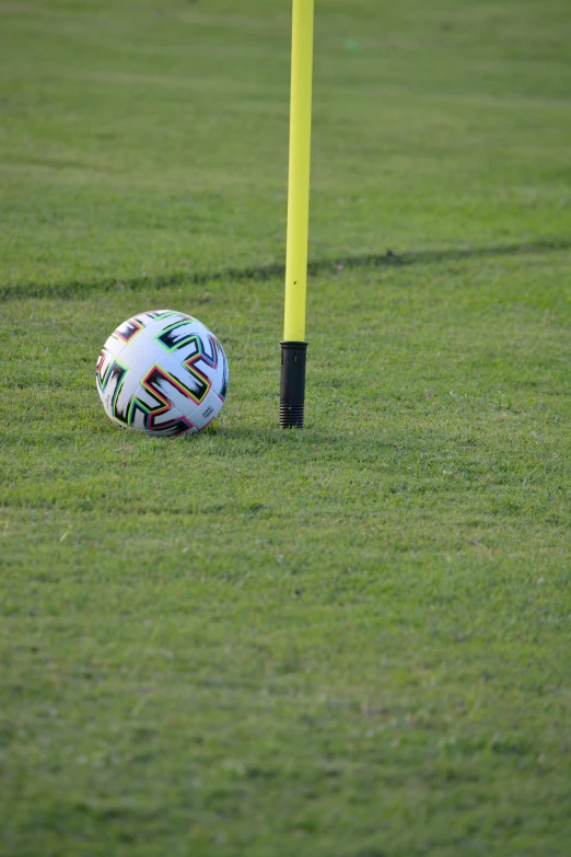 a white soccer ball sitting next to a yellow post