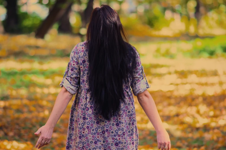 a woman with long hair walking through an open field