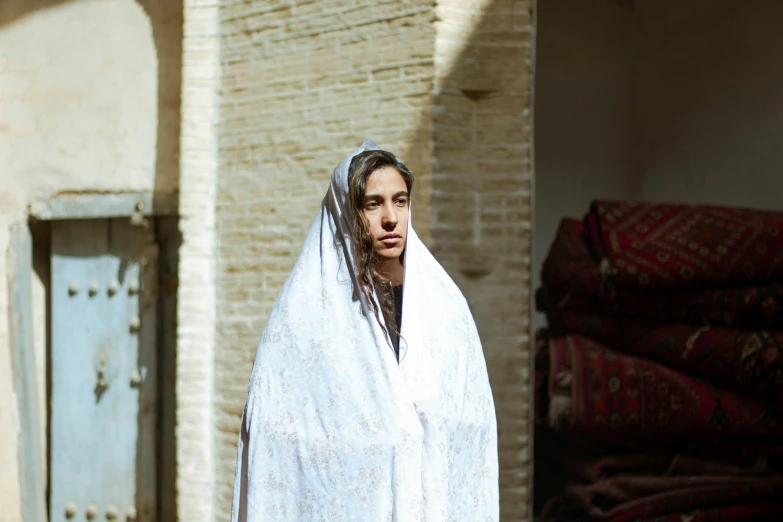 a woman dressed in white and wearing a shawl in a courtyard