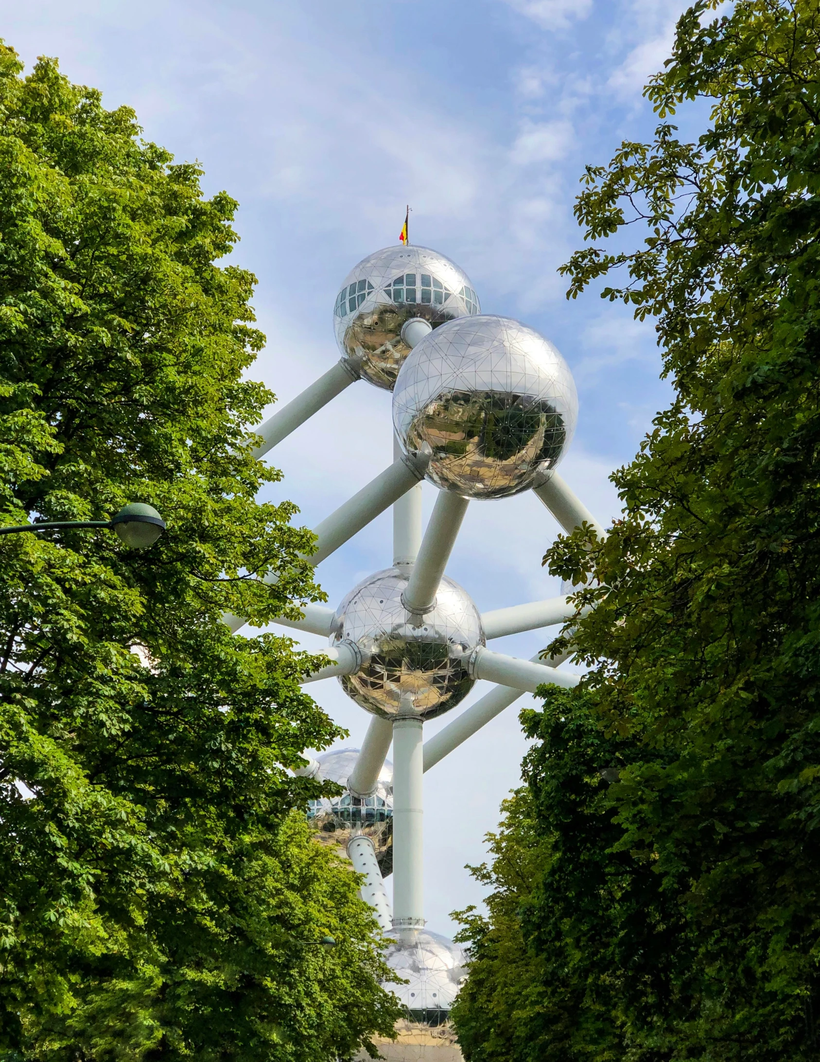 a po taken from the ground, of a walkway between trees and a sculpture