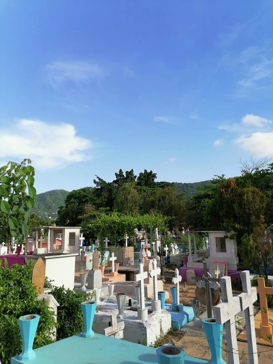 a cemetery of blue and white crosses in a hill country